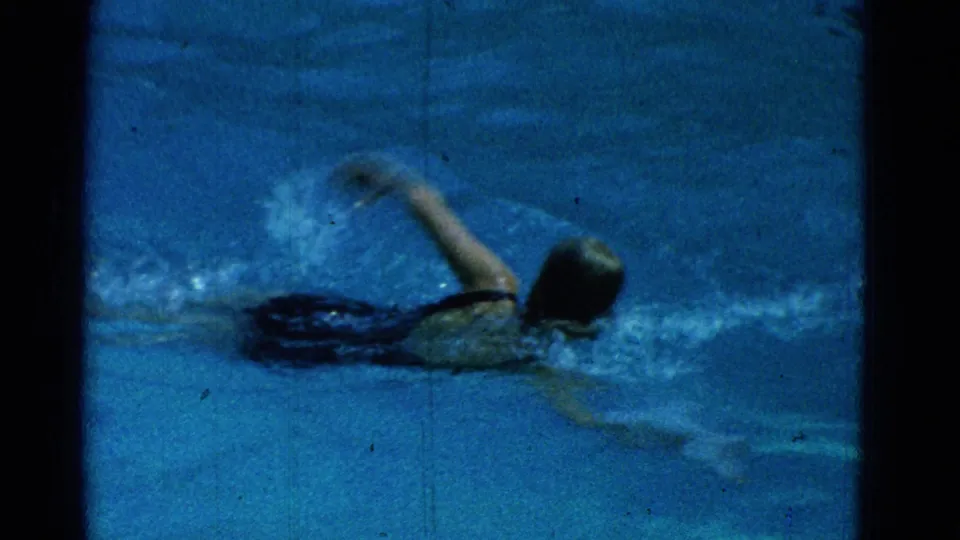 1953 Yonkers 8mm frame with a swimmer close to camera, arm lifted in freestyle and water splashing around the body.