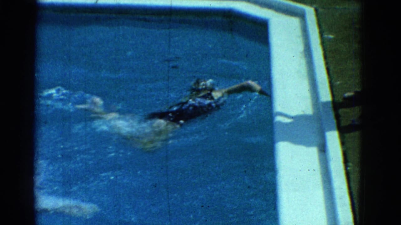 1953 Yonkers home-movie frame showing a swimmer practicing freestyle in a blue residential pool beside white coping.