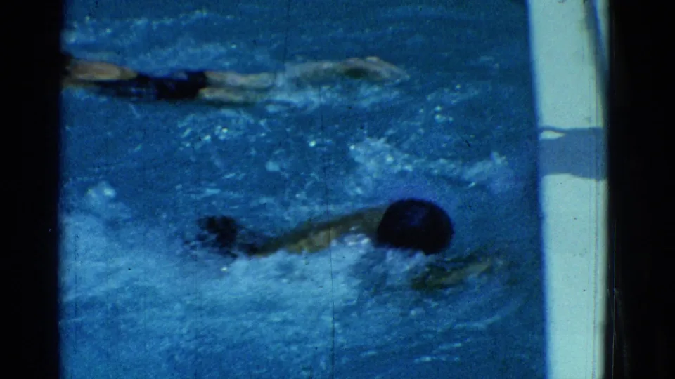 1953 Yonkers residential pool footage showing swimmers in dark suits practicing strokes in bright blue water.