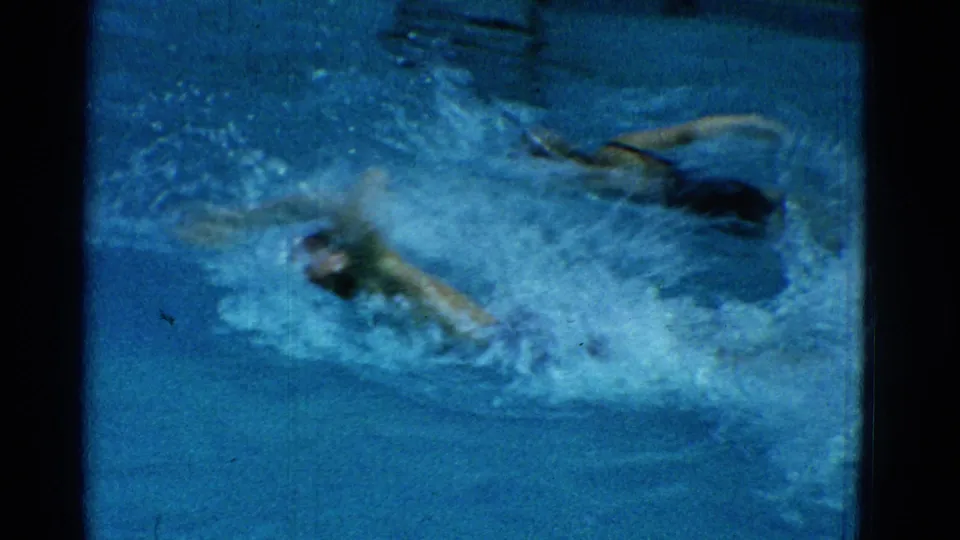 1953 Yonkers home-movie frame with a swimmer partly obscured by splashing water during pool practice.