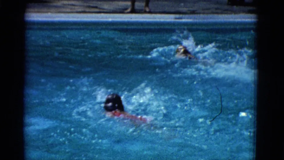 1953 Yonkers 8mm frame with one swimmer lower in the pool and another splashing ahead near the right side of the water.