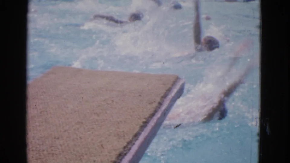 1953 Yonkers swim meet footage shows a backstroke swimmer close to the pool edge with another swimmer farther up the lane.