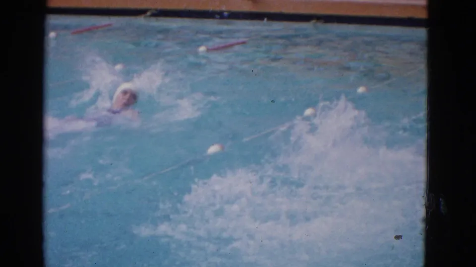 The Yonkers swim-school clip shows the capped swimmer near the lane line, with a second burst of water spray filling the pool foreground.