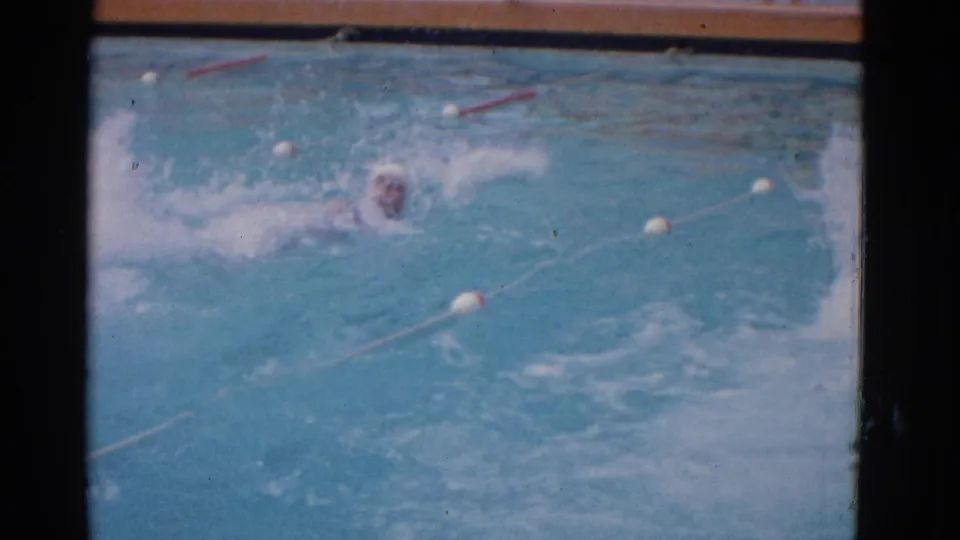 A capped swimmer practices across the marked Yonkers pool lane, with white floats and fading 8mm color visible in the final frame.