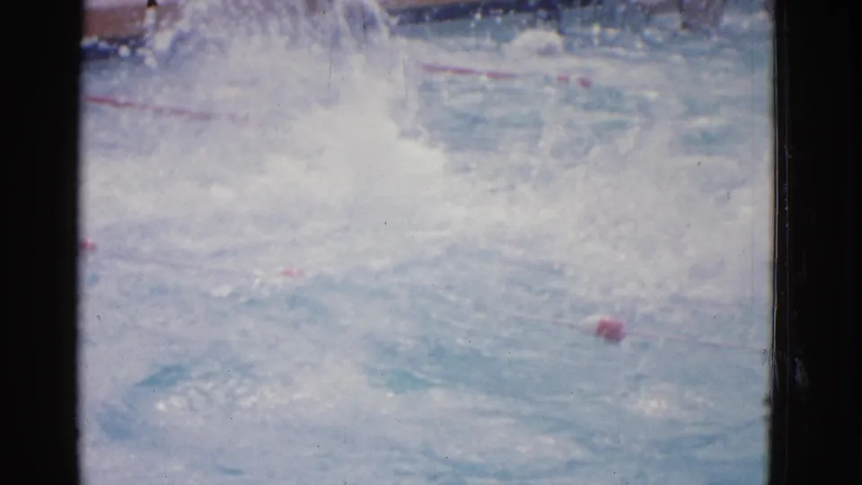 Yonkers swimming pool scene with turbulent water, red lane markers, and a swimmer mostly obscured by splash.