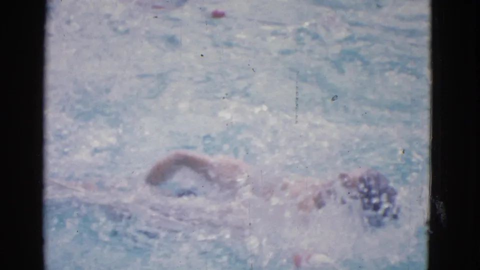 1953 Yonkers 8mm frame showing the swimmer continuing across the pool, with spray and a blurred freestyle motion.
