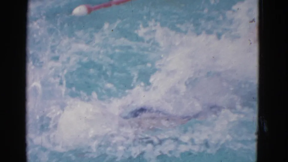 1953 Yonkers home-movie frame with the swimmer mostly hidden by bright splashes during backyard pool practice.