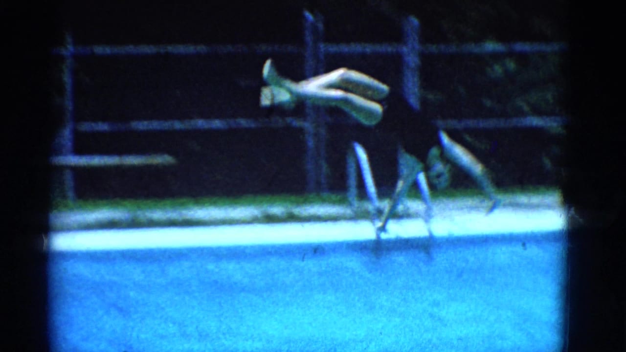1953 Yonkers 8mm frame showing a swimmer mid-flip over a blue backyard pool with ladder rails and fencing behind.