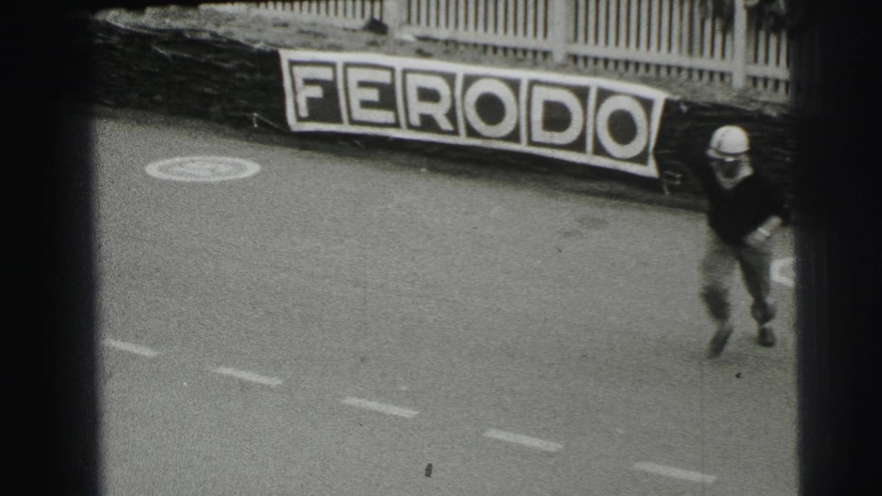 Helmeted driver runs across a racetrack near a Ferodo sign.