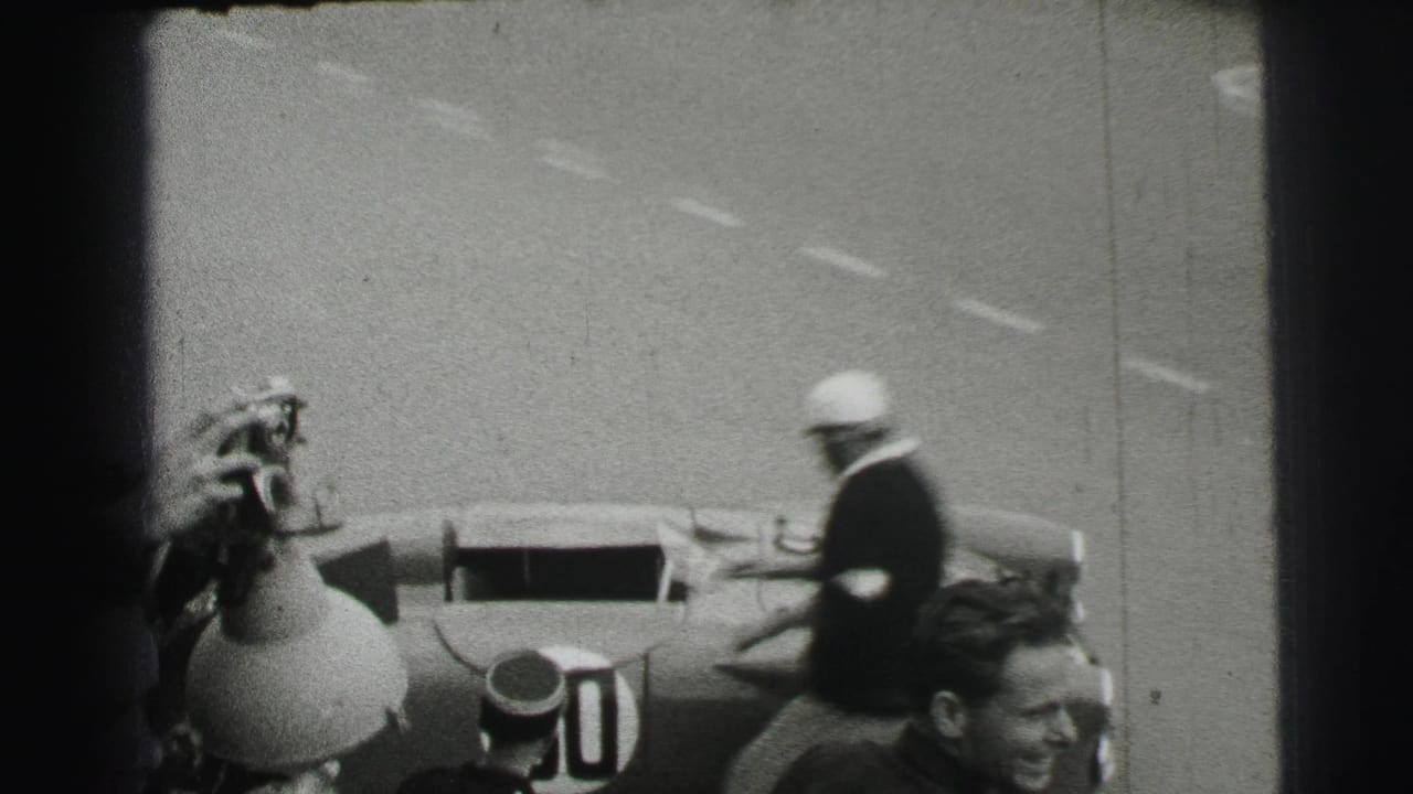 Helmeted driver approaches open racing car number 50 near trackside figures.