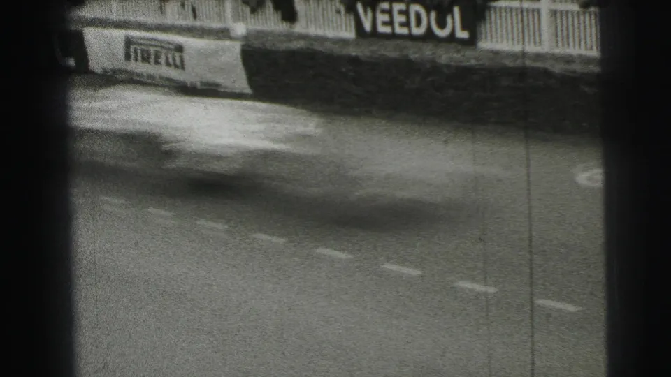 A fast-moving race car blurs across the Le Mans track, with Pirelli and Veedol sponsor boards behind it.
