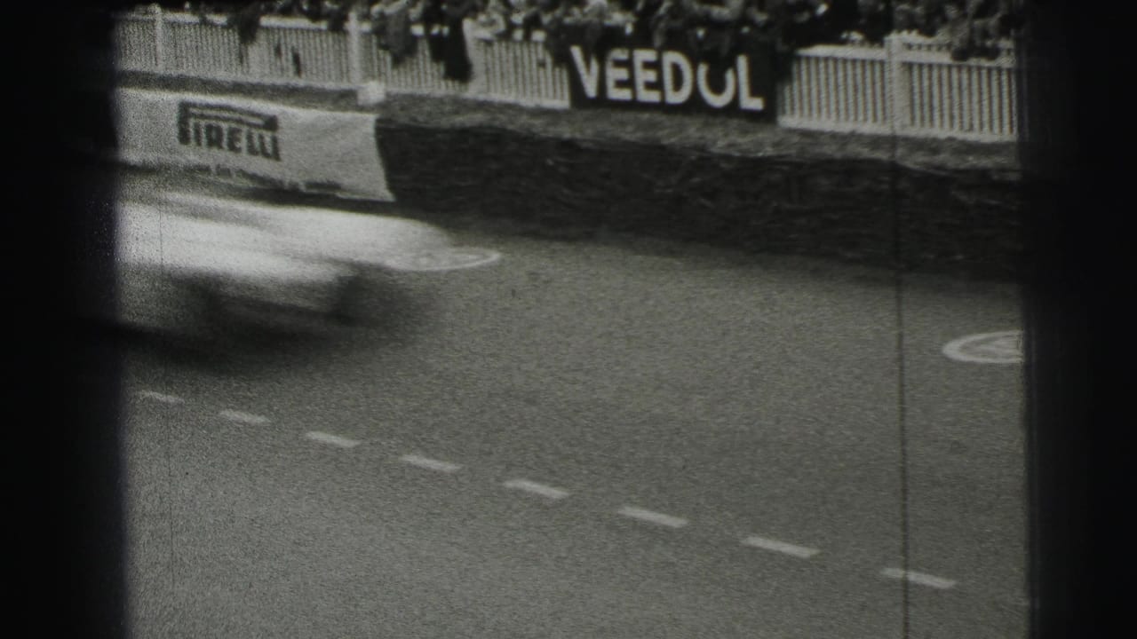 Blurred race car passes a marked track beside Pirelli and Veedol signs.
