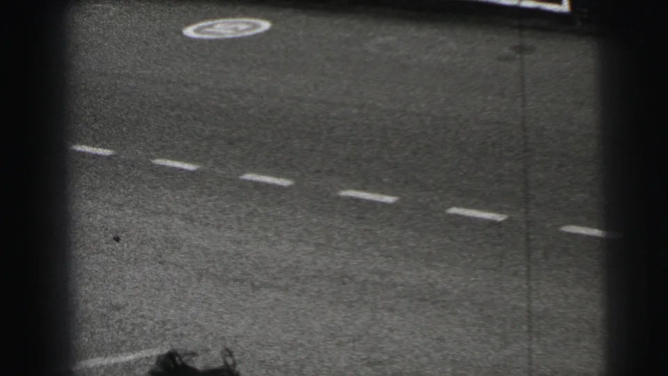 Final 1954 Le Mans frame after the pass, showing an empty paved track with dashed markings and a circular painted symbol.