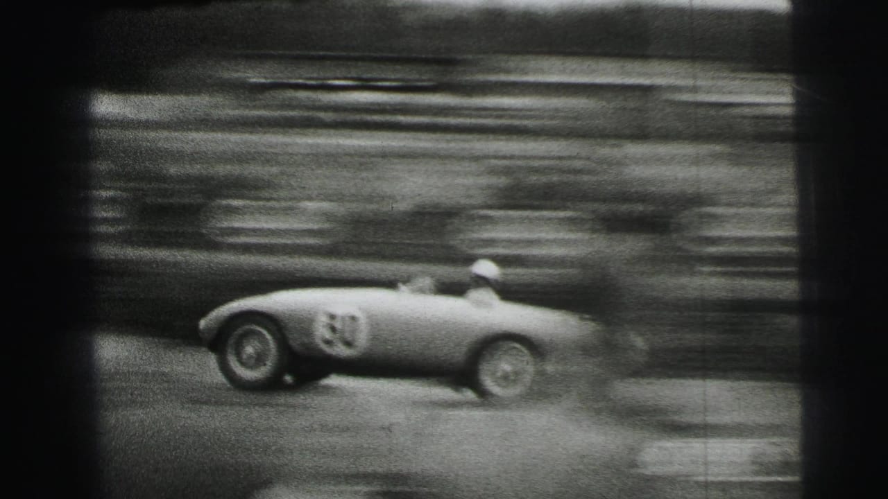 A light-colored open race car, marked with a visible number, passes quickly on the Le Mans circuit with strong motion blur.