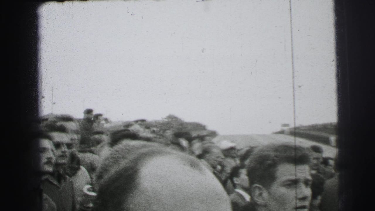 Le Mans spectators in 1950s clothing crowd near the course, with faces and heads filling the foreground of the handheld frame.