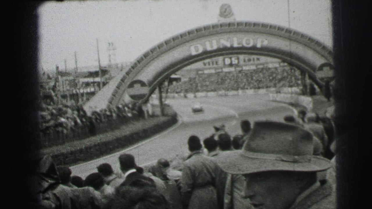 The Dunlop arch spans a curving section of the Le Mans circuit, with spectators lining the barriers and a car visible on the track.