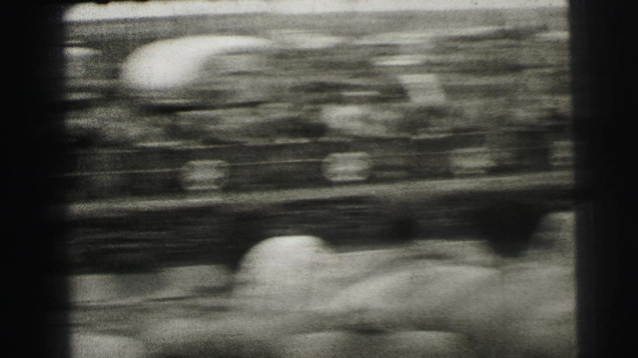 Blurred 8mm frame from Le Mans showing a racing car passing close to trackside spectators, with motion streaks across the scene.