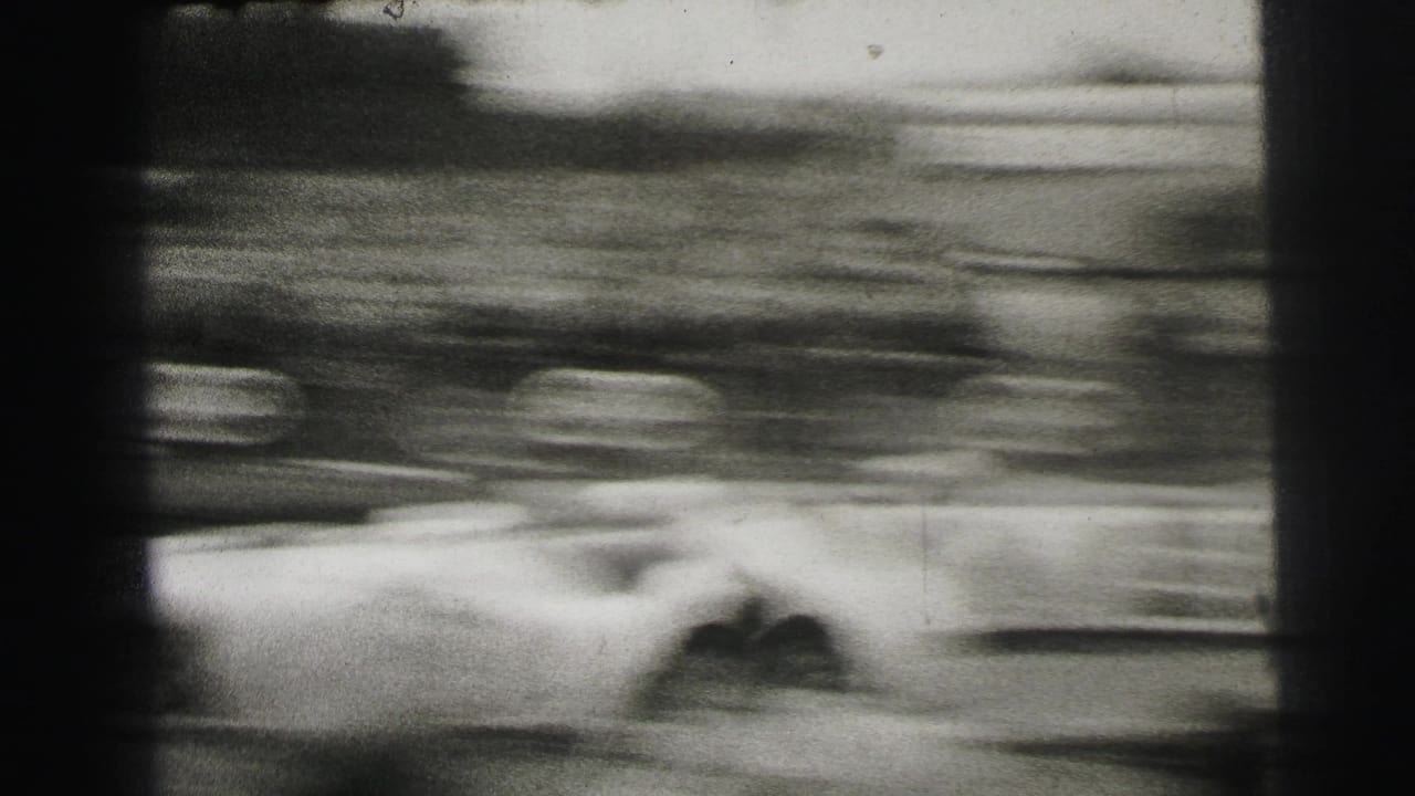 Blurred race car passing trackside crowd at high speed.