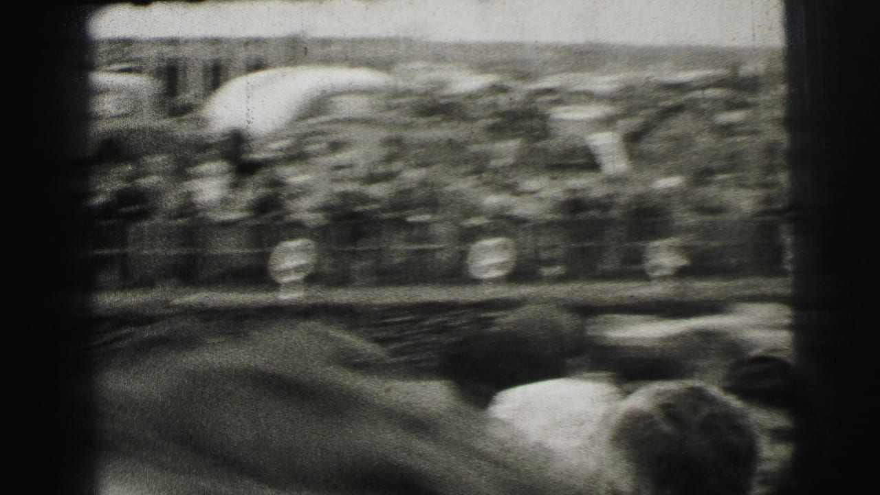 A race car flashes past a dense Le Mans crowd, captured with heavy motion blur on 8mm film.
