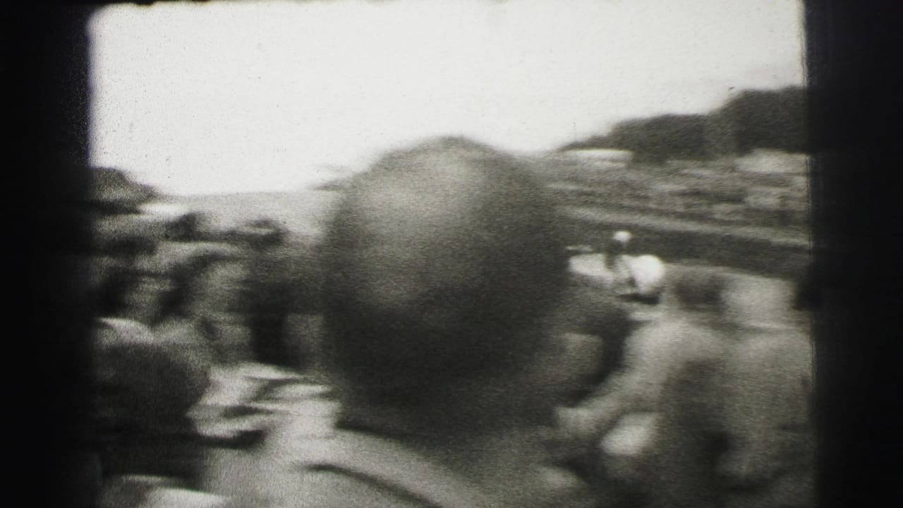 Handheld Le Mans spectator angle looking over heads toward the circuit, with the crowd and track partly obscured by foreground viewers.