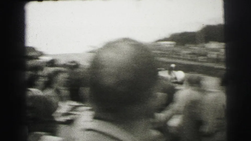Handheld Le Mans spectator angle looking over heads toward the circuit, with the crowd and track partly obscured by foreground viewers.