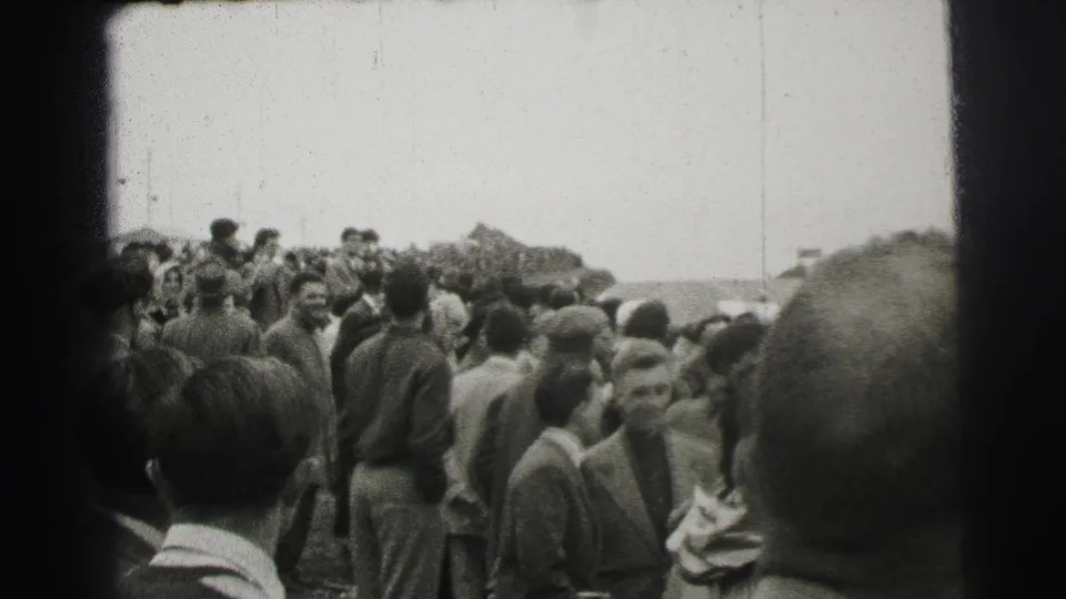 1954 Le Mans spectators stand closely together near the course, with faces and period clothing visible in black-and-white 8mm footage.