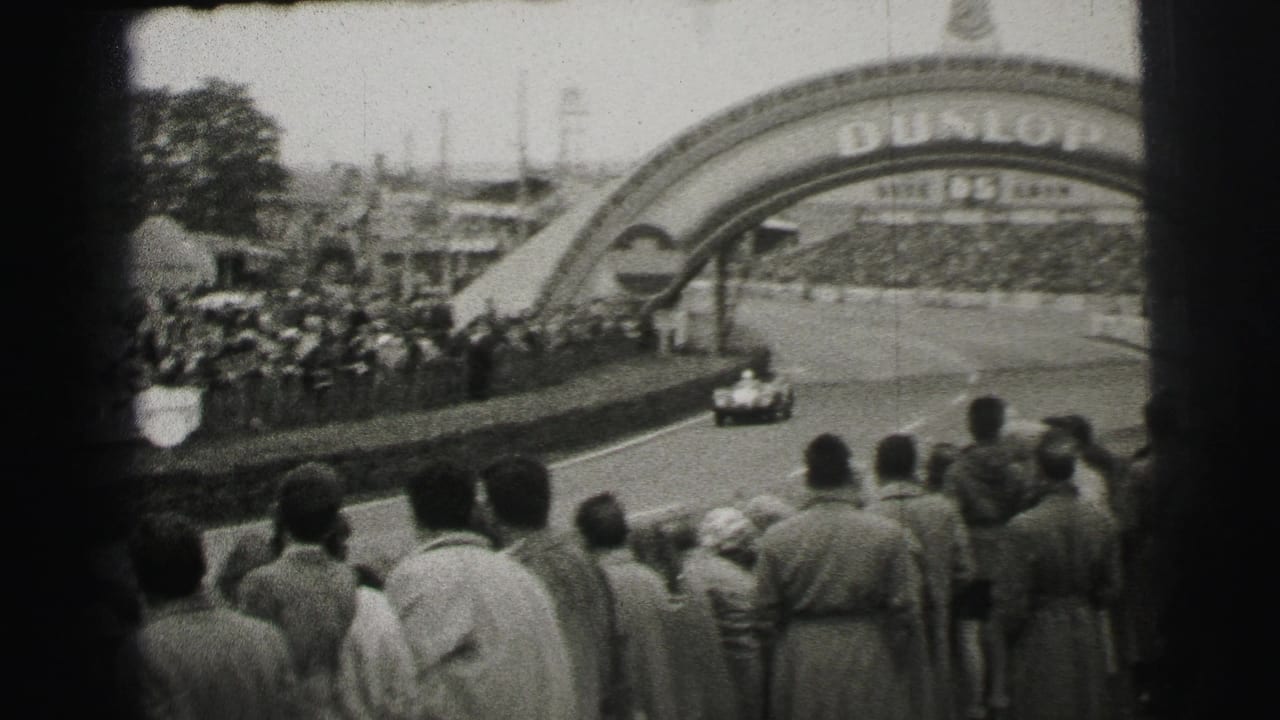 At Le Mans in 1954, a race car approaches the Dunlop-branded arch while spectators stand along the paved course.