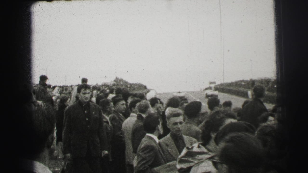 Spectators stand beside a racetrack, with several faces and period coats visible.