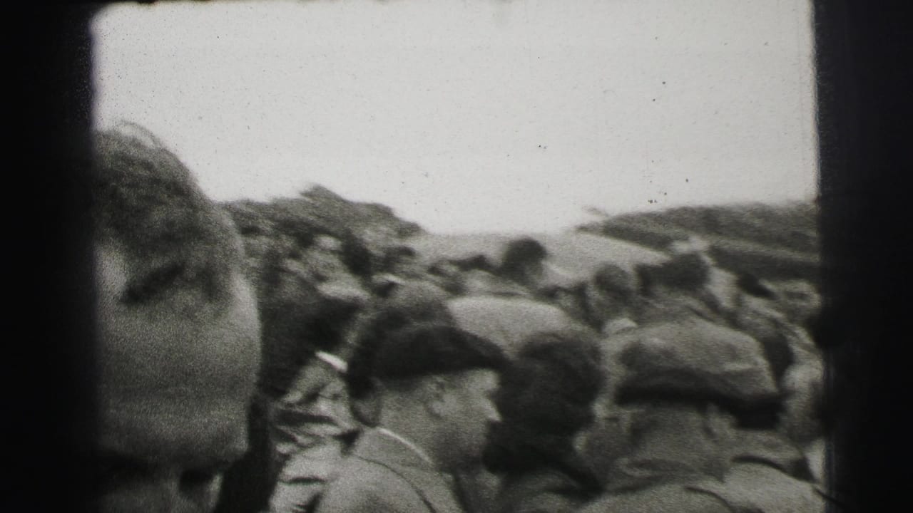 Crowd of spectators standing beside a racecourse, with a man's face partly entering the foreground.