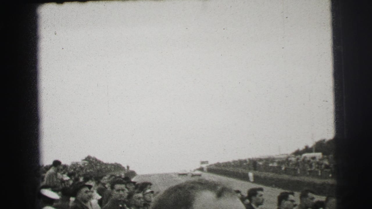 Black-and-white 1950s Le Mans crowd scene with spectators packed near the course and foreground heads partly blocking the view.