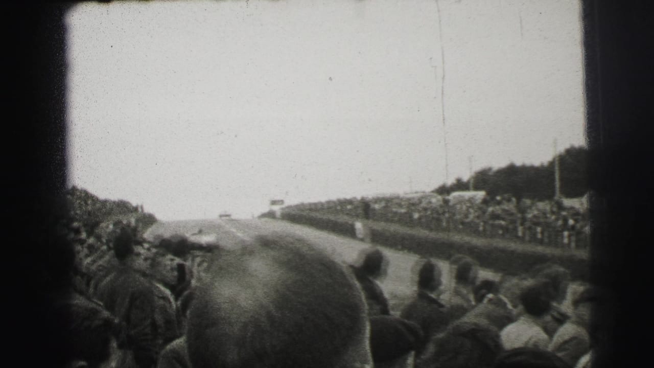 Crowd-lined race track with a car visible in the distance.
