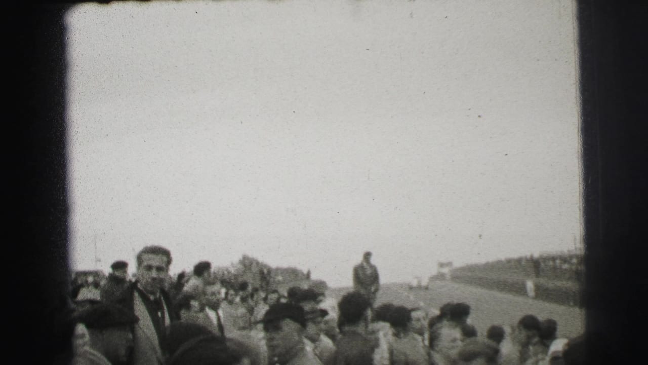 1954 Le Mans home-movie frame showing spectators along the track, with a man in a dark coat facing the camera.