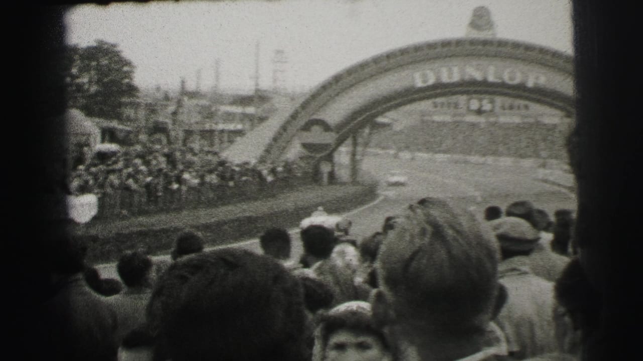 1954 Le Mans frame with spectators watching from near the Dunlop bridge as a race car approaches on the track.