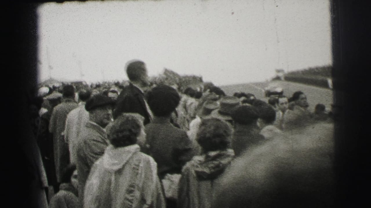 1954 Le Mans home-movie view of spectators in coats and hats gathered beside the racetrack.