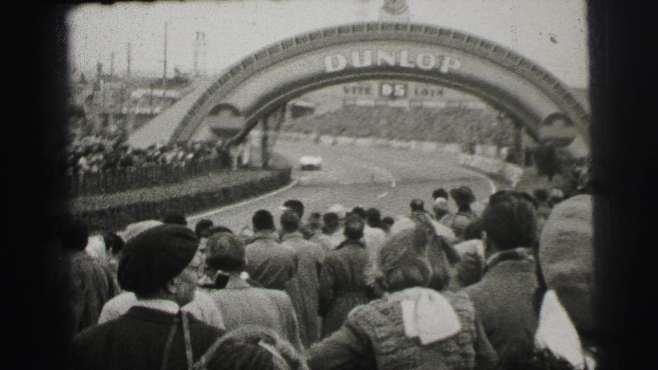 At Le Mans, spectators line the track as a light-colored race car approaches the Dunlop bridge signage.