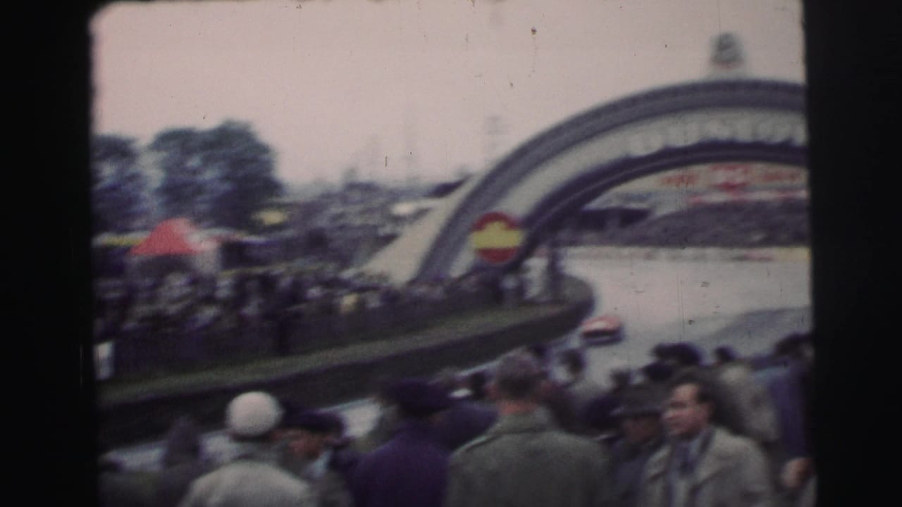 Spectators watch a race car pass near the Dunlop arch at Le Mans.
