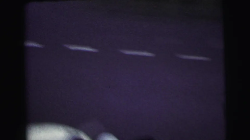 Soft 8mm frame from the Le Mans clip showing dark pavement, white markings, and a blurred vehicle edge.