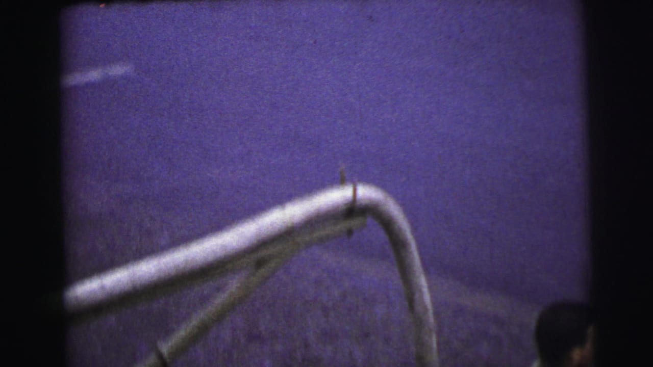 Soft 1954 Le Mans 8mm frame showing a curved white race car body detail with dim exposure and heavy grain.