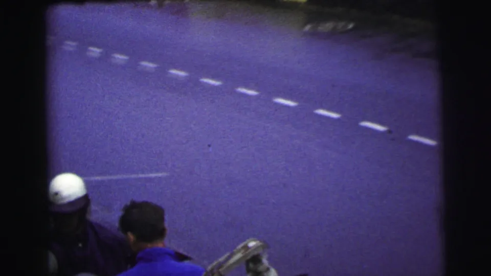 The final frame looks across the Le Mans track surface, with lane markings and partial people at the lower edge.