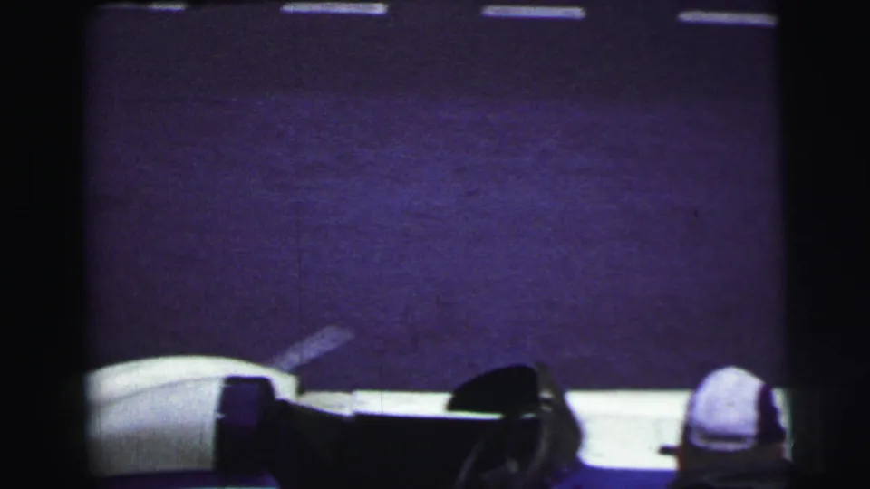 At Le Mans in 1954, the frame catches mostly track surface with the race car edge and helmeted figure partly visible below.
