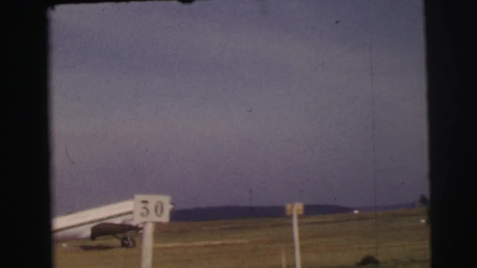 1954 Le Mans frame showing the rear of a passenger aircraft moving across the airfield behind the 50 marker sign.
