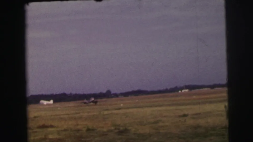 8mm home-movie view of a small aircraft continuing its takeoff roll on a rural Le Mans grass airstrip in 1954.