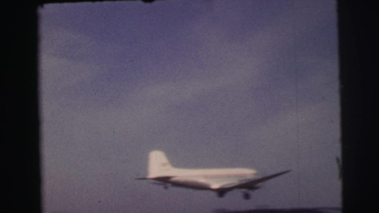 1954 8mm footage from Le Mans, France, showing a small propeller airplane lifting into a pale sky above an open field.