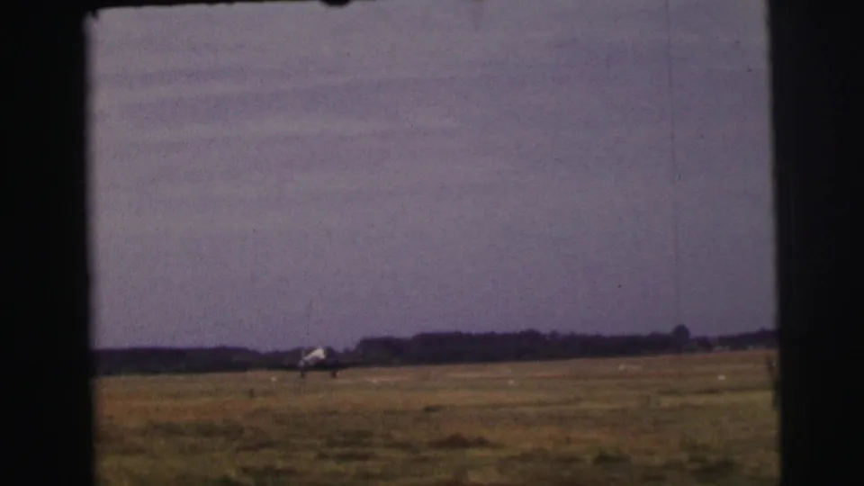 Final 1954 Le Mans frame showing a small propeller airplane near the horizon across an open rural field.