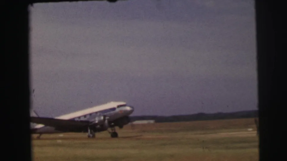 The aircraft fills more of the frame as it taxis on the grassy airfield, with dark 8mm borders and a muted cloudy sky.