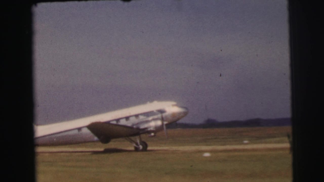 The aircraft continues along the Le Mans airfield runway, with landing gear visible against open grass and a low horizon.