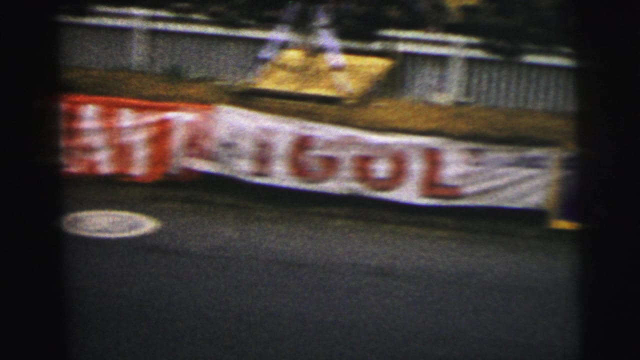 Blurred trackside advertising banners along a race circuit barrier.