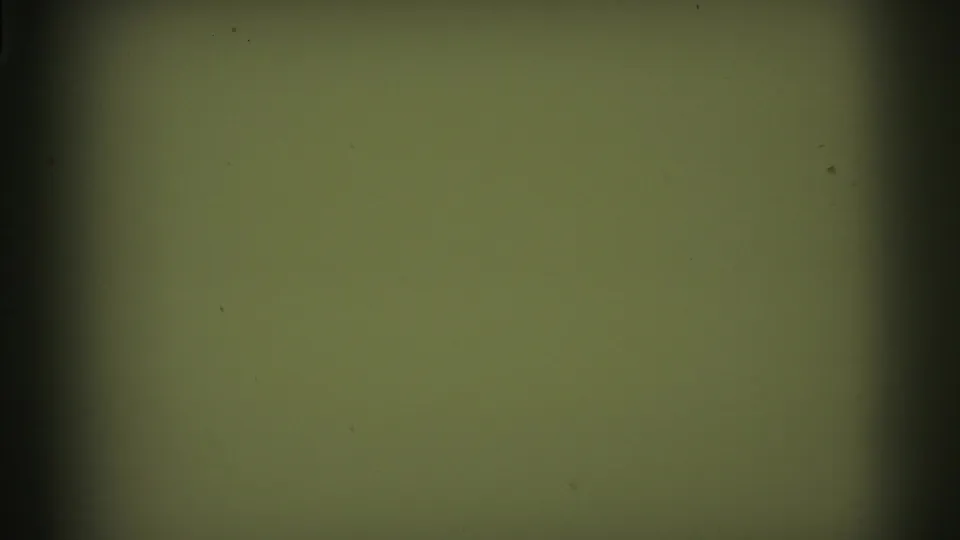 Green-tinted blank or overexposed 8mm frame with dark gate edges and visible dust or specks.