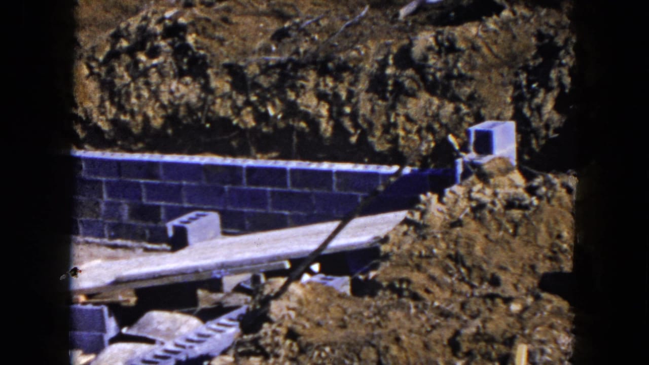 Cinder block foundation, wooden planks and excavated soil at a construction site.