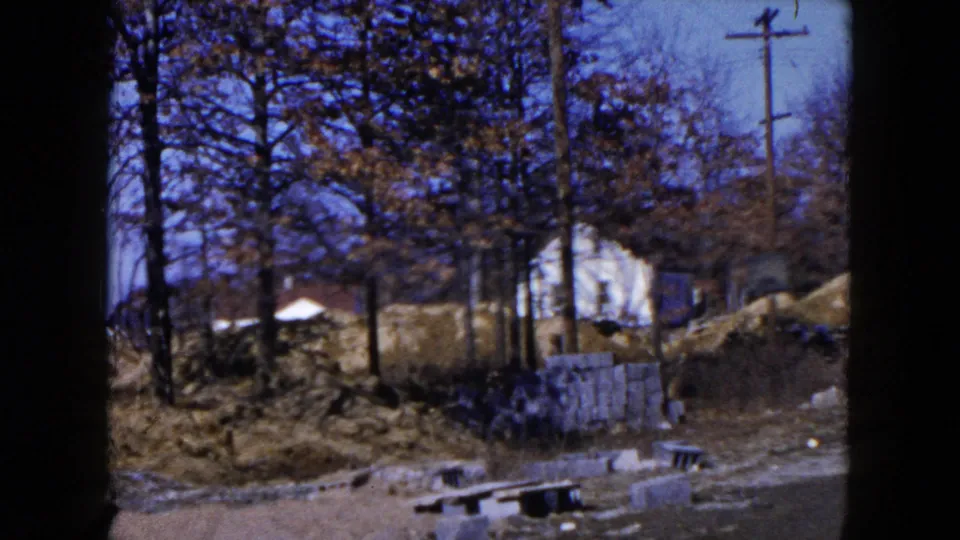 Hicksville, New York construction site with concrete blocks, bare trees, dirt piles, a white house, and a utility pole.